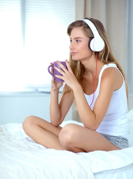 自宅のベッドの上に座って音楽を聴く朝で美しい女性の肖像画 — ストック写真