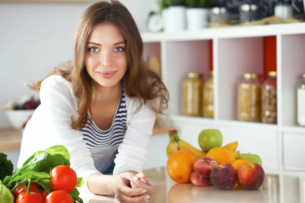 Jonge vrouw zit in de buurt van bureau in de keuken — Stockfoto