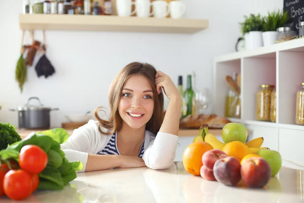 Jonge vrouw zit in de buurt van bureau in de keuken — Stockfoto