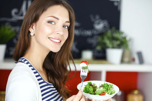 Ung kvinna äta sallad och hålla en blandad sallad — Stockfoto