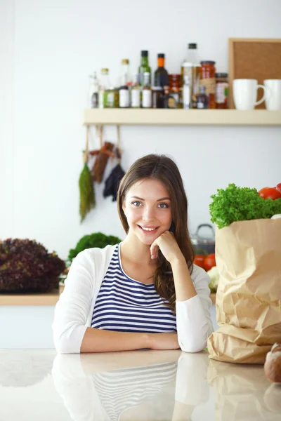 Молодая женщина сидит возле стола на кухне — стоковое фото