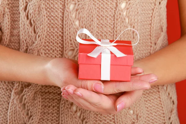 Vrouwelijke hand met luxe-geschenketui geïsoleerd op rode achtergrond — Stockfoto