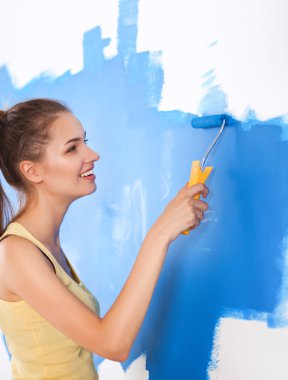 Mutlu güzel bir kadın duvar boyuyor.