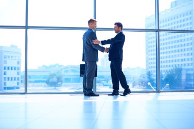 İki başarılı iş adamının el sıkışırken tam boy görüntüsü.