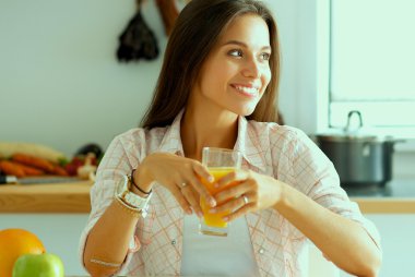 Genç bayan mutfakta masanın yanında oturuyor.