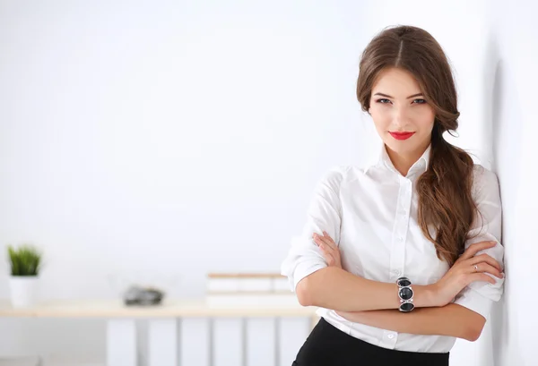 Attractive businesswoman standing near wall in office — Stock Photo, Image