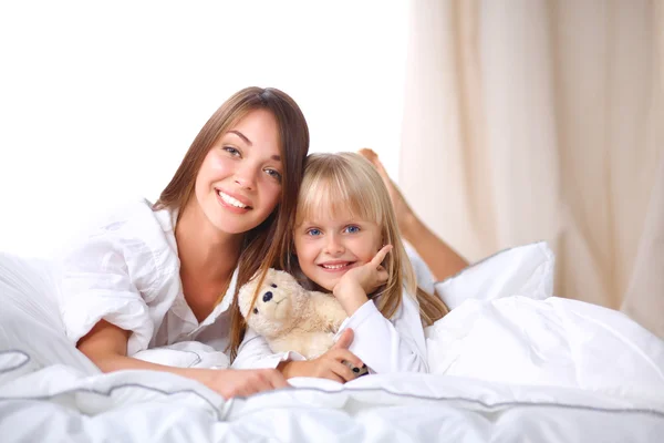 Woman and young girl lying in bed smiling — Stock Photo, Image