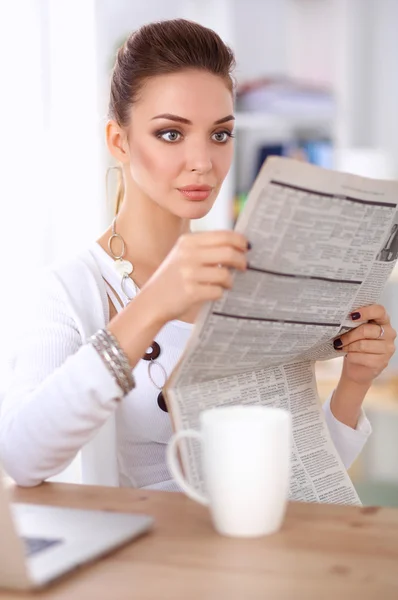 Cute businesswoman holding newspaper sitting at her desk in office — Stock Photo, Image