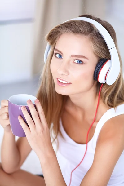 Portret van mooie vrouw in de ochtend luisteren muziek zittend op bed thuis — Stockfoto