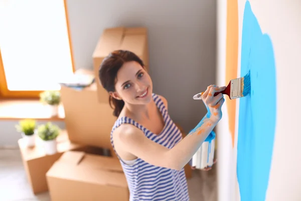 Счастливая улыбающаяся женщина расписывает внутреннюю стену нового дома — стоковое фото