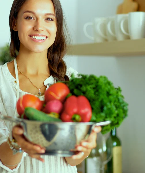 Lächelnde junge Frau mit Gemüse in der Küche — Stockfoto