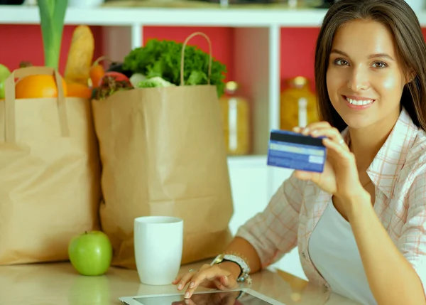 Smiling woman online shopping using tablet and credit card in kitchen — Stock Photo, Image