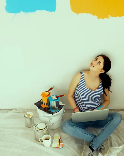 Portrait de jeune femme tout en peignant un nouvel appartement, assis avec ordinateur portable — Photo