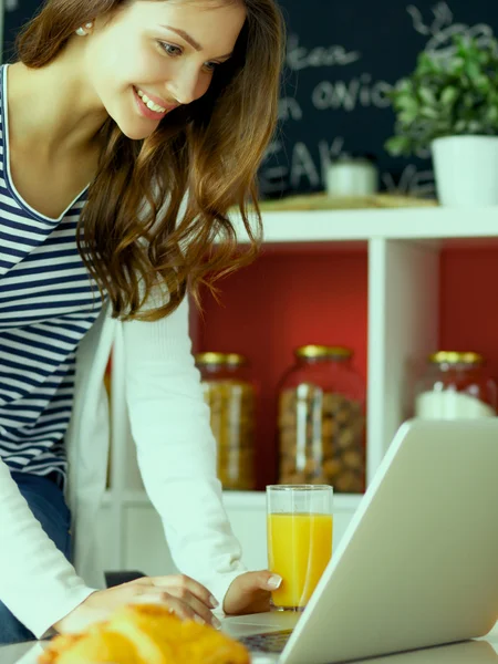 Jonge vrouw zit in de buurt van bureau in de keuken — Stockfoto