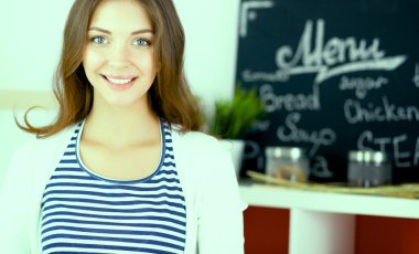 Mutfakta masanın yanında duran genç bir kadın.