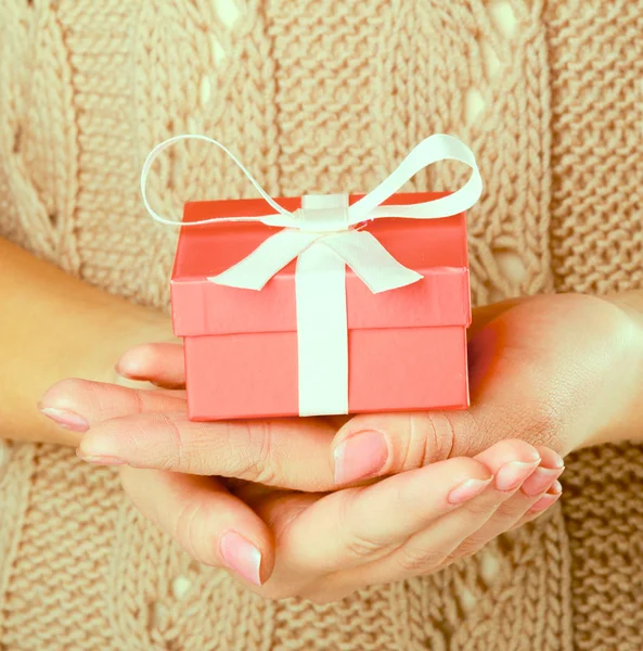 Female hand holding gift box isolated on red background — Stock Photo, Image