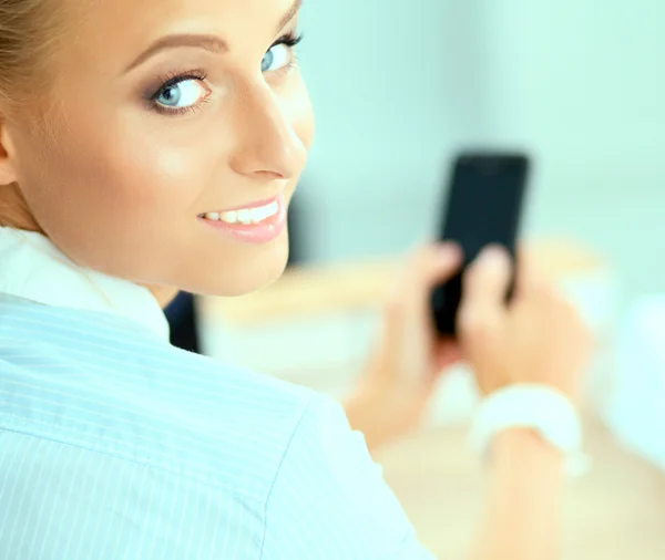 Zakenvrouw stuurt bericht met smartphone zittend op kantoor — Stockfoto