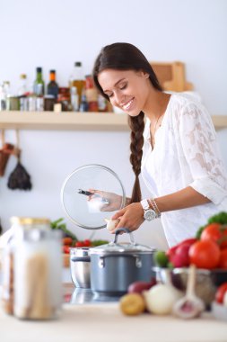 Mutfakta sobanın yanında duran genç bir kadın.