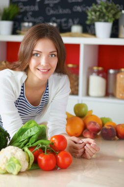 Mutfakta masanın yanında duran genç bir kadın.