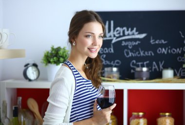 Güzel kadın mutfakta şarap içiyor. .