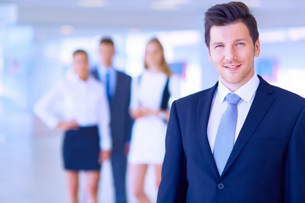 Portret van jonge zakenman in kantoor met collega's op de achtergrond — Stockfoto