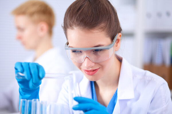 Woman researcher is surrounded by medical vials and flasks, isolated on white background