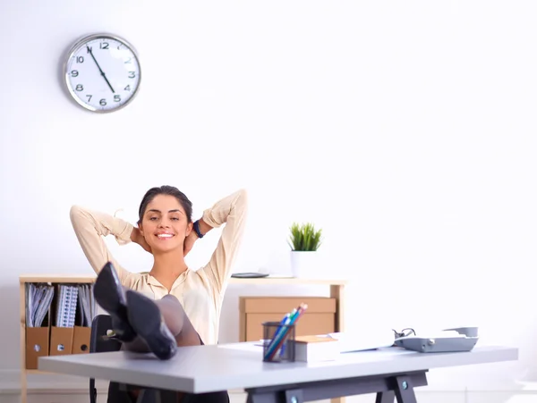 Geschäftsfrau entspannt sich mit den Händen hinter dem Kopf und sitzt auf einem Bürostuhl — Stockfoto
