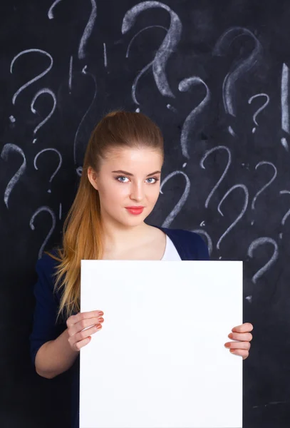 Young girl with question mark holding a blank on gray background