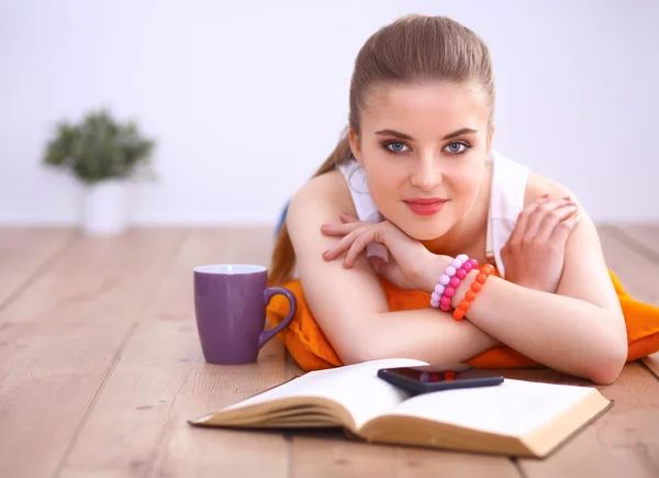 Smiling young woman lying on a white floor with pillow — Stock Photo, Image