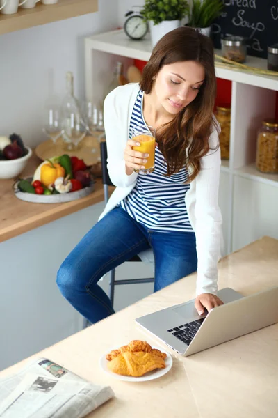 Mujer joven sentada cerca de escritorio en la cocina — Foto de Stock