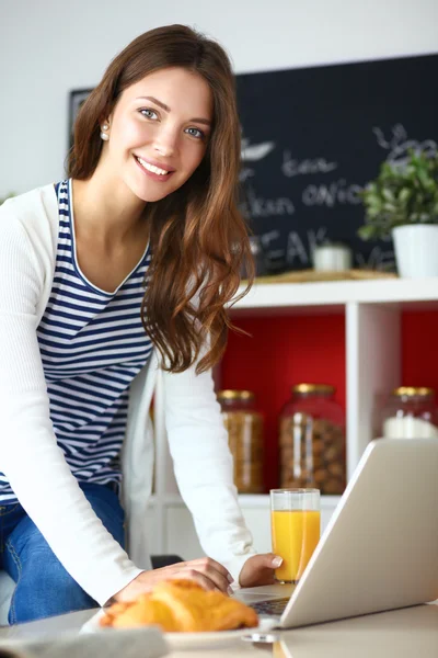 Giovane donna seduta vicino alla scrivania in cucina — Foto Stock