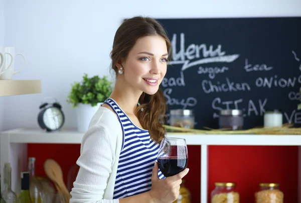 Mujer bonita bebiendo un poco de vino en casa en la cocina . —  Fotos de Stock