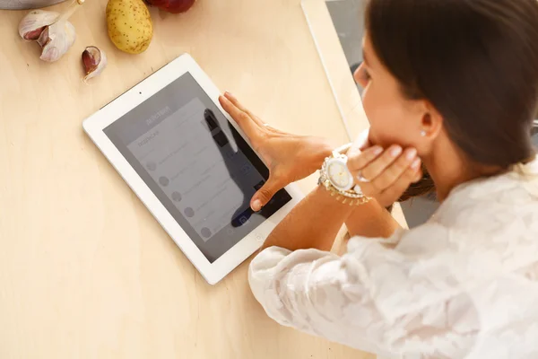 Giovane donna che utilizza un tablet per cucinare nella sua cucina . — Foto Stock