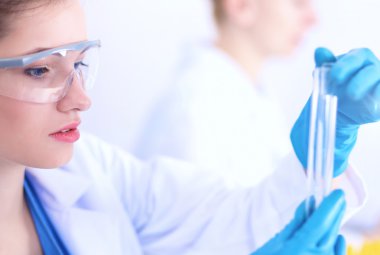 Kadın araştırmacı, beyaz arka planda izole edilmiş ilaç şişeleri ve mataralarla çevrili.