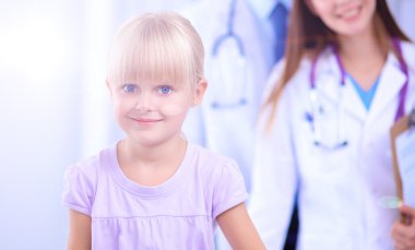 Kadın doktor ameliyatta steteskopla çocuğu muayene ediyor.