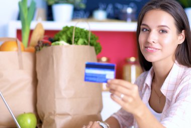 Gülümseyen kadın mutfakta tablet ve kredi kartı kullanarak alışveriş online