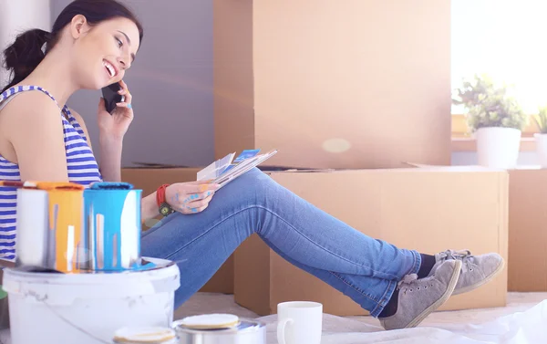 Vrouw verf kleur kiezen uit staal voor nieuwe huis zittend op houten vloer — Stockfoto