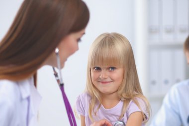 Kadın doktor ameliyatta steteskopla çocuğu muayene ediyor.