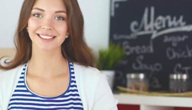 Mutfakta masanın yanında duran genç bir kadın.