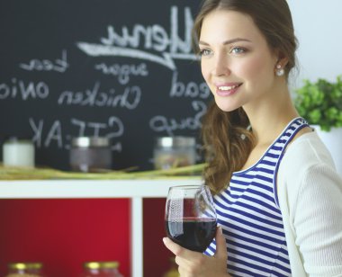 Güzel kadın mutfakta şarap içiyor.