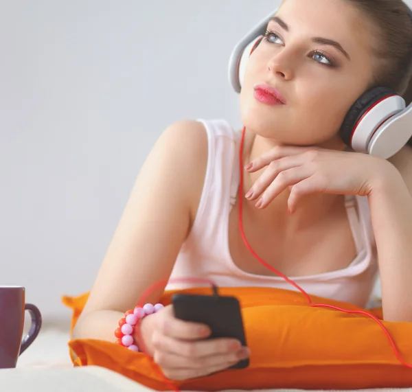 Retrato de una hermosa mujer en la mañana escuchando música sentada en la cama en casa — Foto de Stock