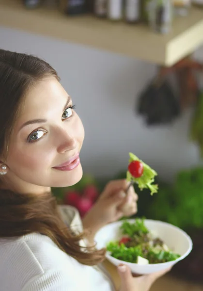 Jovem comendo salada e segurando uma salada mista — Fotografia de Stock