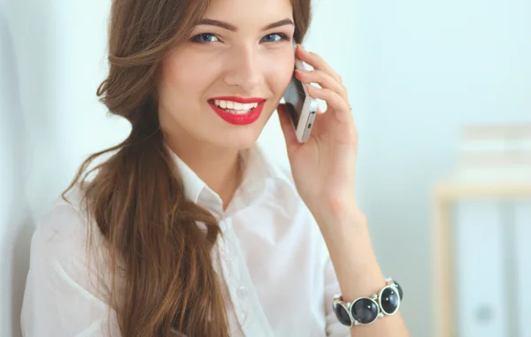 Усміхнена бізнес-леді розмовляє по телефону в офісі — стокове фото