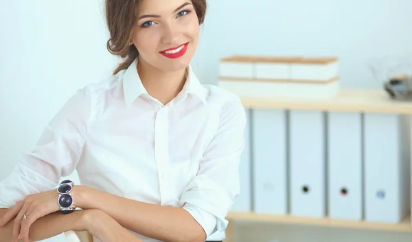 Attraktive Geschäftsfrau steht an Wand im Büro — Stockfoto