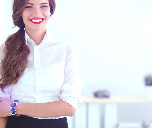 Attractive businesswoman standing near wall in office — Stock Photo, Image