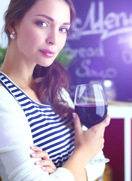 Mulher bonita bebendo um pouco de vinho em casa na cozinha — Fotografia de Stock