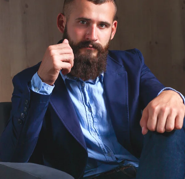 Affärsman som sitter i soffan i kontoret lobbyn, isolerad på mörk bakgrund — Stockfoto