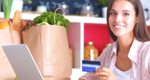 Smiling woman online shopping using tablet and credit card in kitchen — Stock Photo, Image