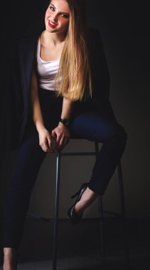 Genç bir kadın sandalyede oturuyor.