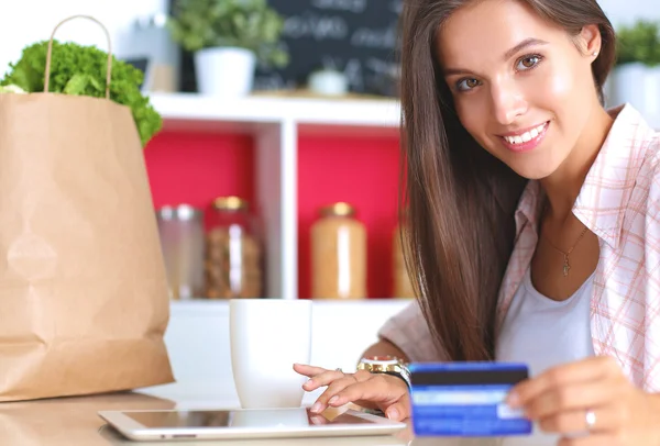 Lächelnde Frau beim Online-Shopping mit Tablet und Kreditkarte in der Küche — Stockfoto